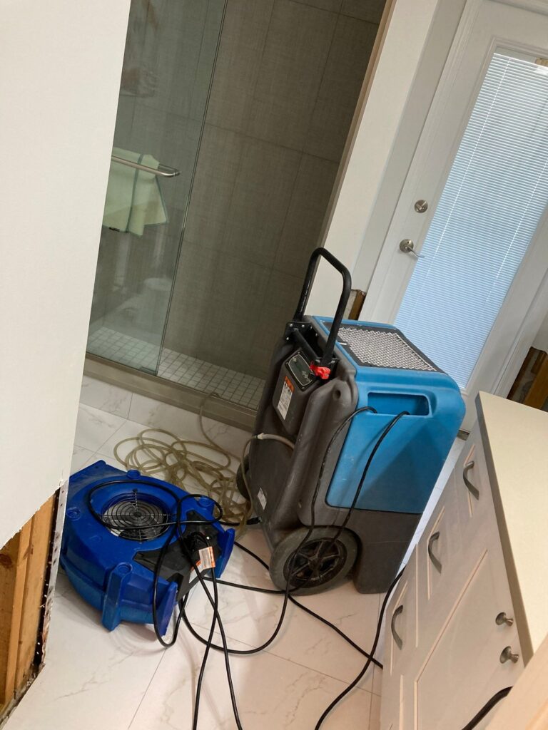 Dehumidifier and air mover drying a bathroom after water damage in Cape Coral, FL